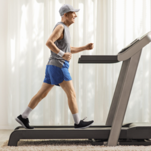 An elderly man jogging on a treadmill in his home