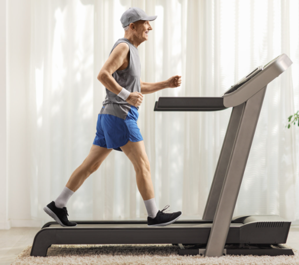 An elderly man jogging on a treadmill in his home